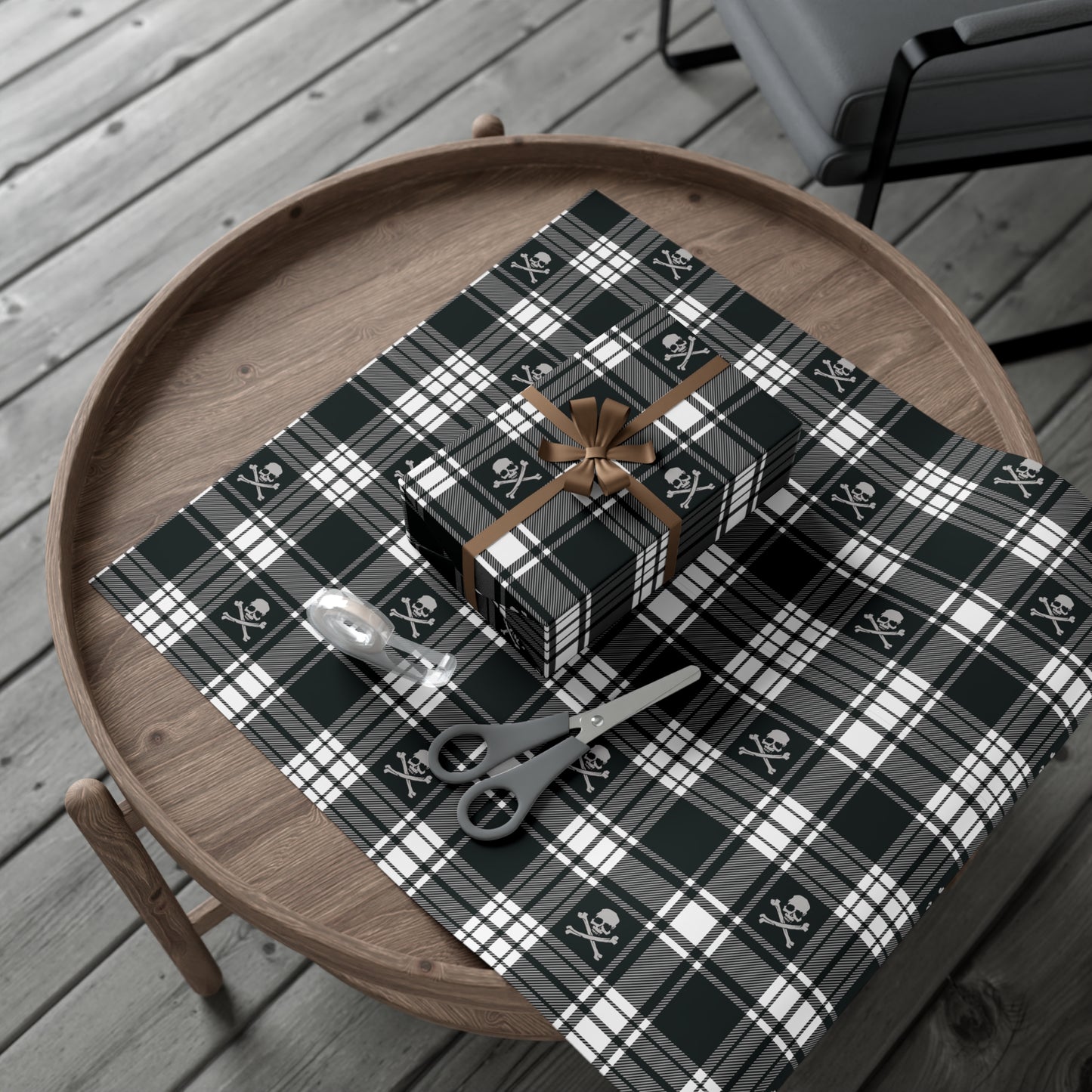 skull and crossbones pirate black and white flannel plaid wrapping paper gift wrapped up on a table with scissor tape and extra paper for another present